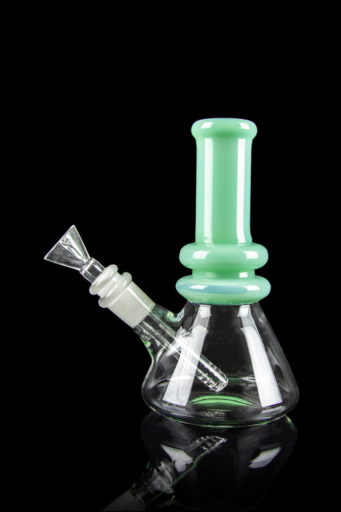 Mint green glass bong with a flared base and detachable bowl, reflecting on a black surface.