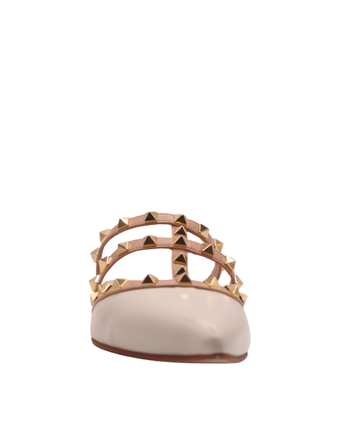 Cream pointed-toe mule with three Beige straps decorated with gold pyramid studs and a low flat. front view
