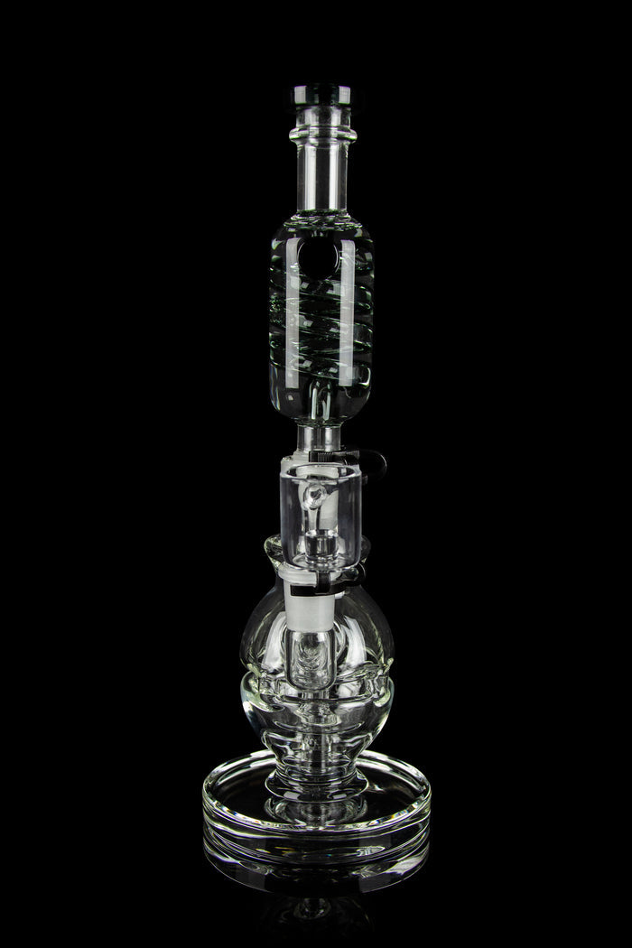Clear glass water pipe (rig) with intricate bubbler design, isolated on black.