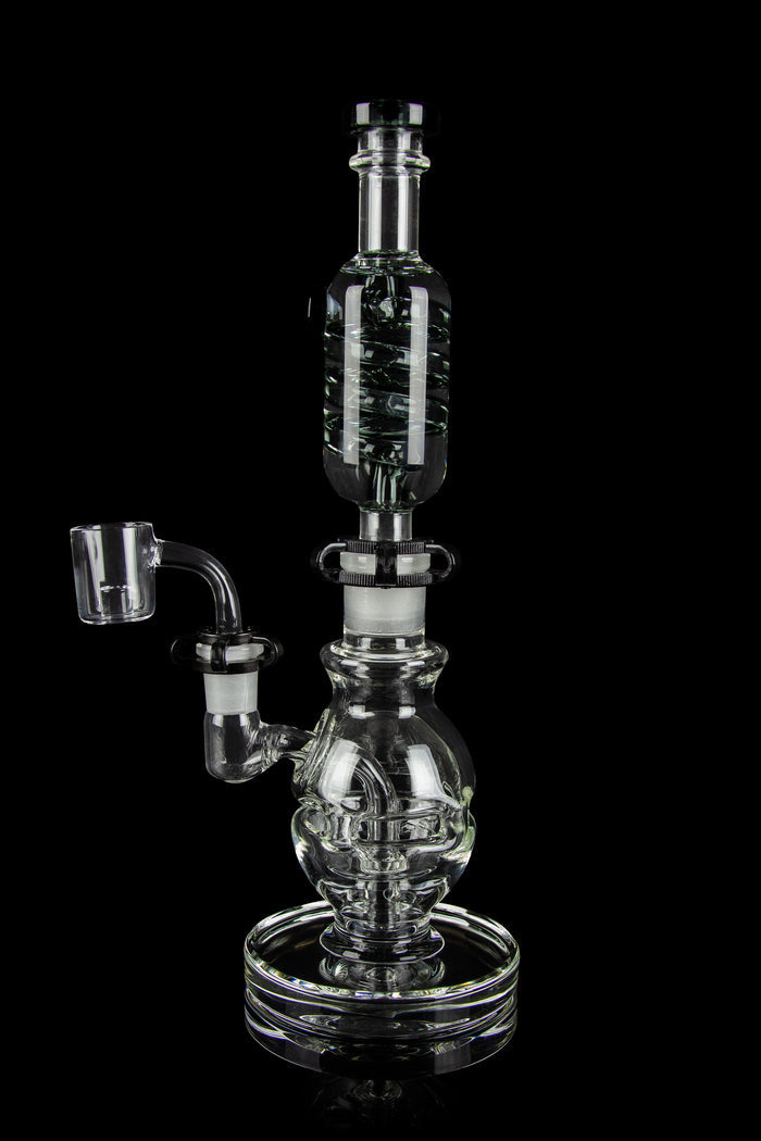 Clear glass dab rig with intricate bubbler design and quartz nail, isolated on black.