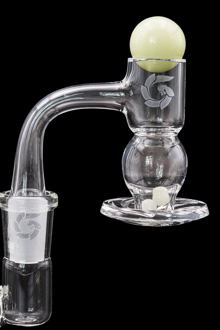 Clear glass dab rig with etched logo and spherical bubbler, alongside white carb caps.