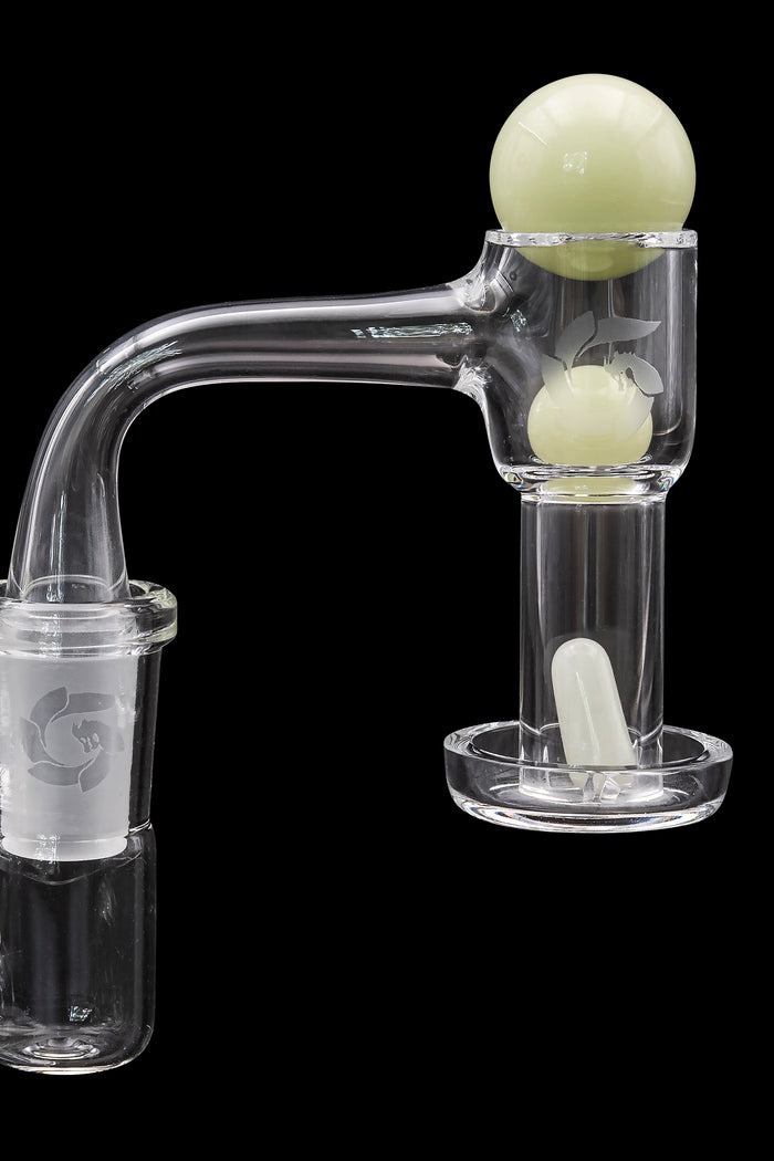 Clear glass dab rig with a spherical green accent and accompanying nail.