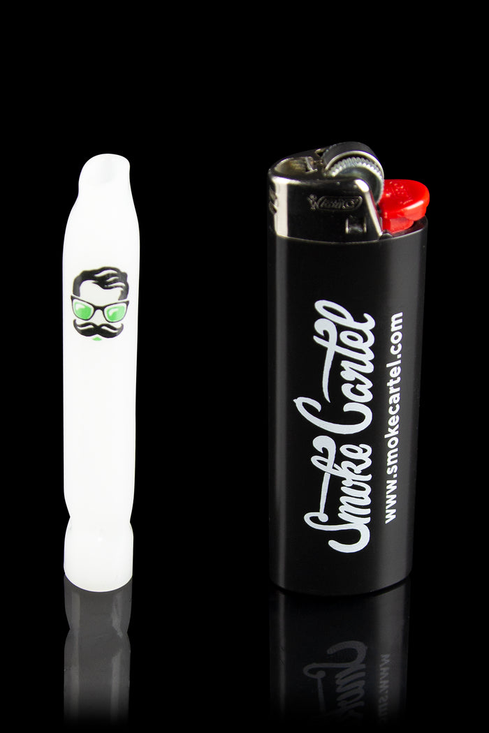White glass pipe with a cartoon face design next to a black lighter branded with “Smoke Cartel” and website address.
