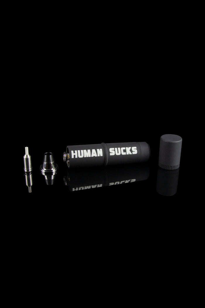 Cannabis oil vape pen components displayed on a black background with "HUMAN SUCKS" printed on the battery.