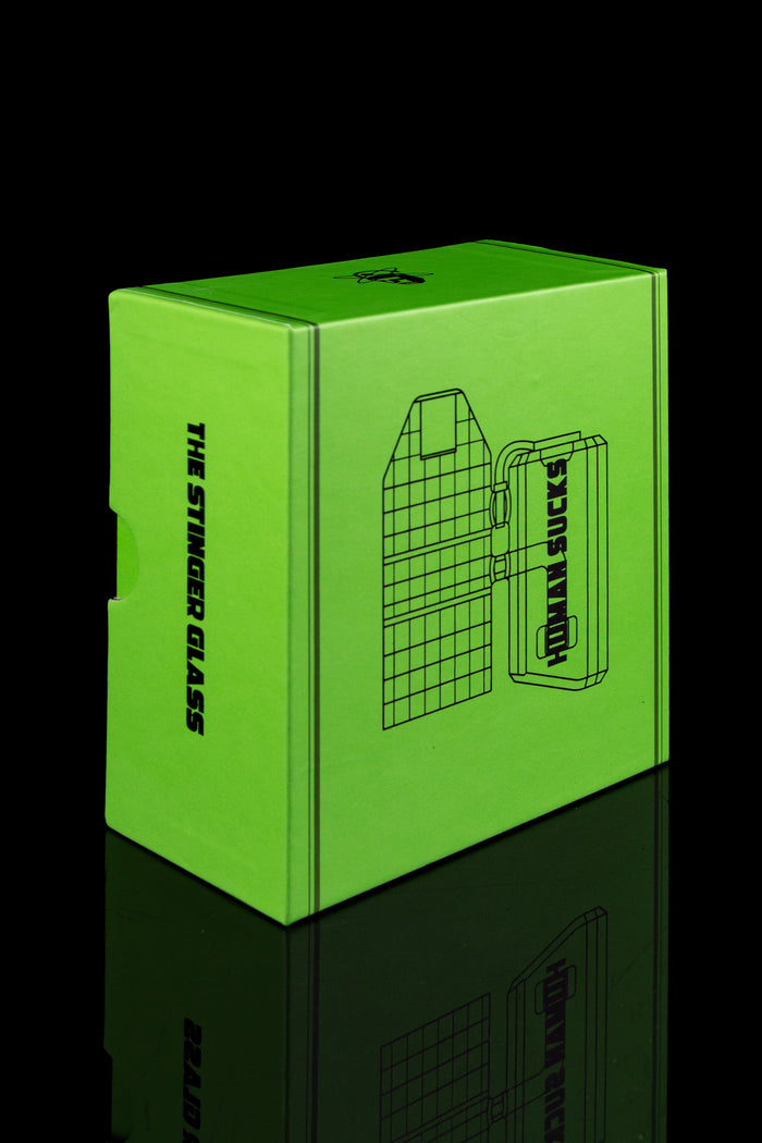 Bright green packaging box for "The Stinger Glass" cannabis accessory with a graphic of a rig and the text "HONKA SUCKS".