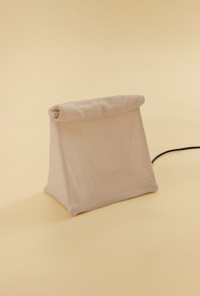 Lunch Bag Lamp made of natural linen fabric, shown unlit with its signature folded top design.