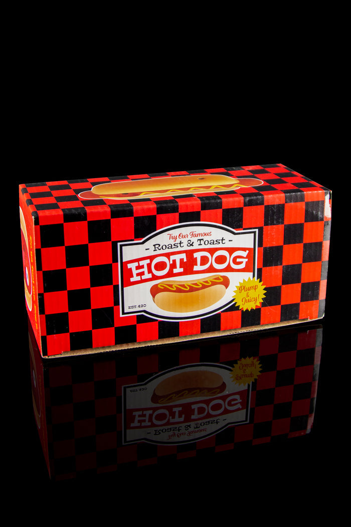 A red and black checkered box labeled “Hot Dog - Roast & Toast” with a cannabis leaf design, reflected on a glossy surface.