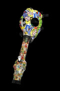 Angled view of a Gas Mask with Acrylic Bong featuring a colorful skull-and-cartoon patterned mask and matching long neck against black.