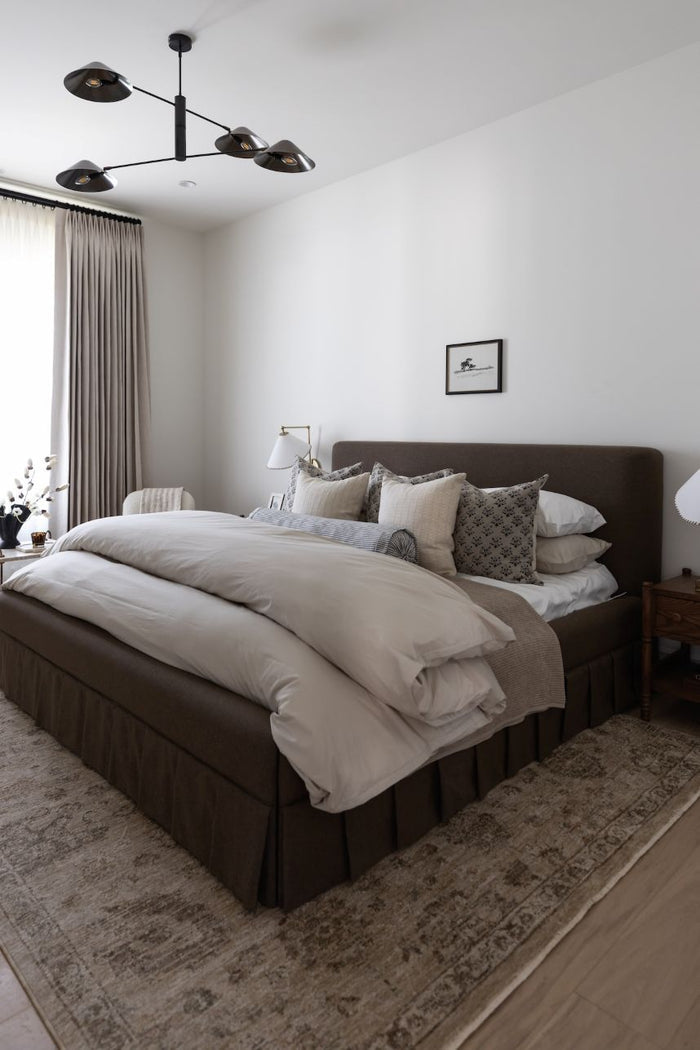 Modern bedroom with a power loomed area rug and bed, side tables, and decorative pillows.